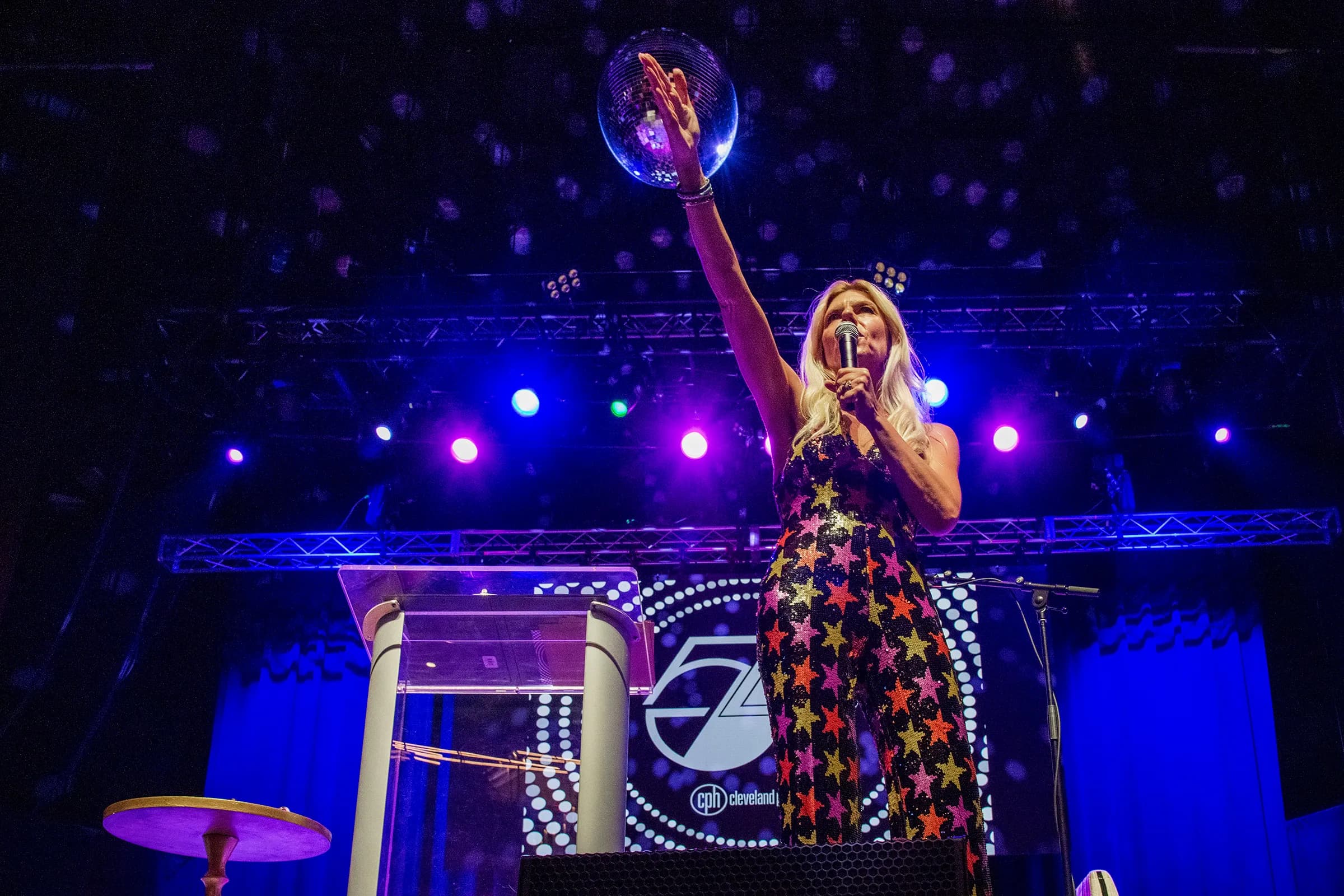 Molly Grantham on stage reaching toward a disco ball, mid-show